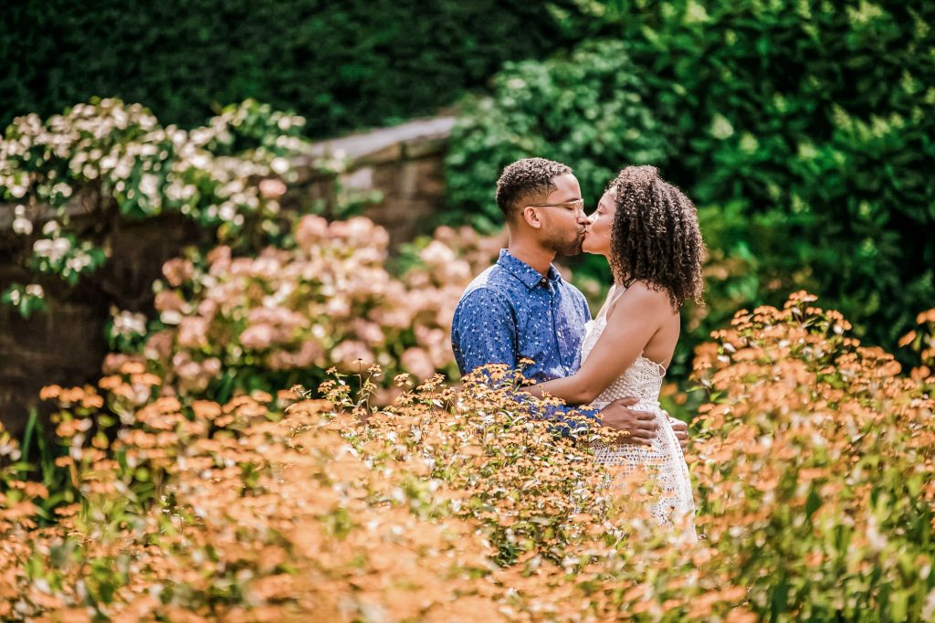 Couple kissing while being surrounded by foliage